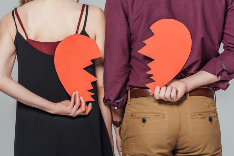 Pareja sosteniendo un corazón roto como representación de una ruptura de pareja.