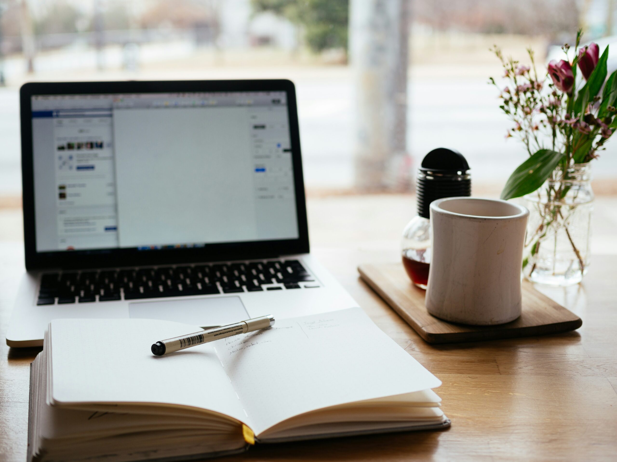 Ordenador portátil y cuaderno preparados para una sesión de terapia psicológica online.